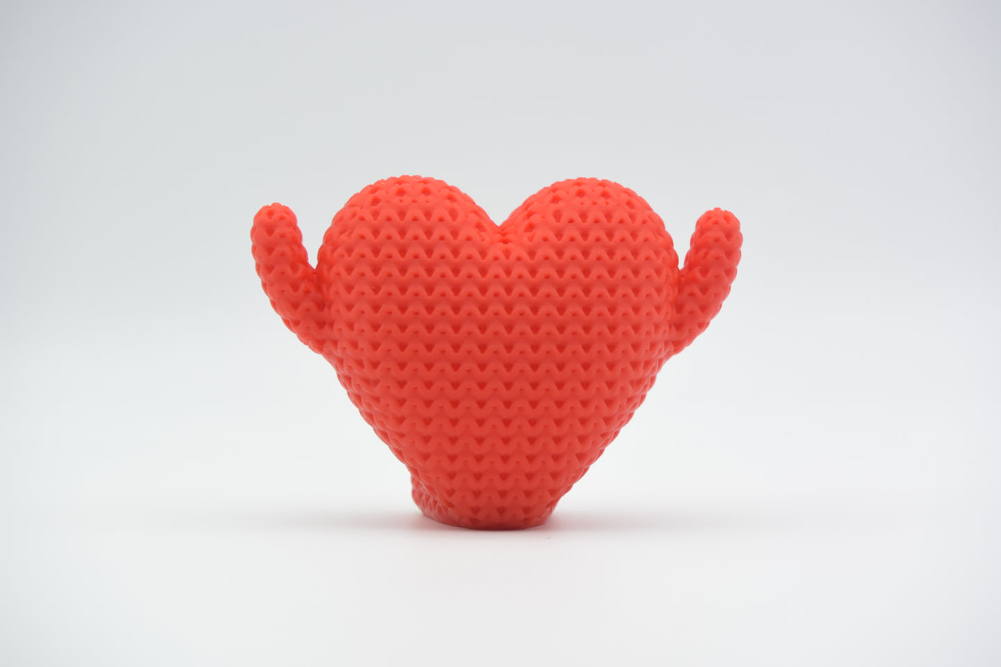 Detail shot of the woven knit texture on a red heart-shaped decorative figure, showing the soft surface pattern