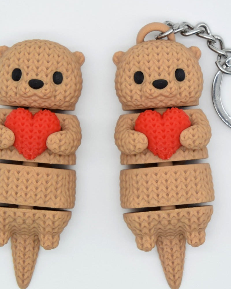 Close-up of a knitted articulated otter holding a small heart, showing soft crochet-texture surface detail