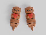 Close-up of a knitted articulated otter holding a small heart, showing soft crochet-texture surface detail