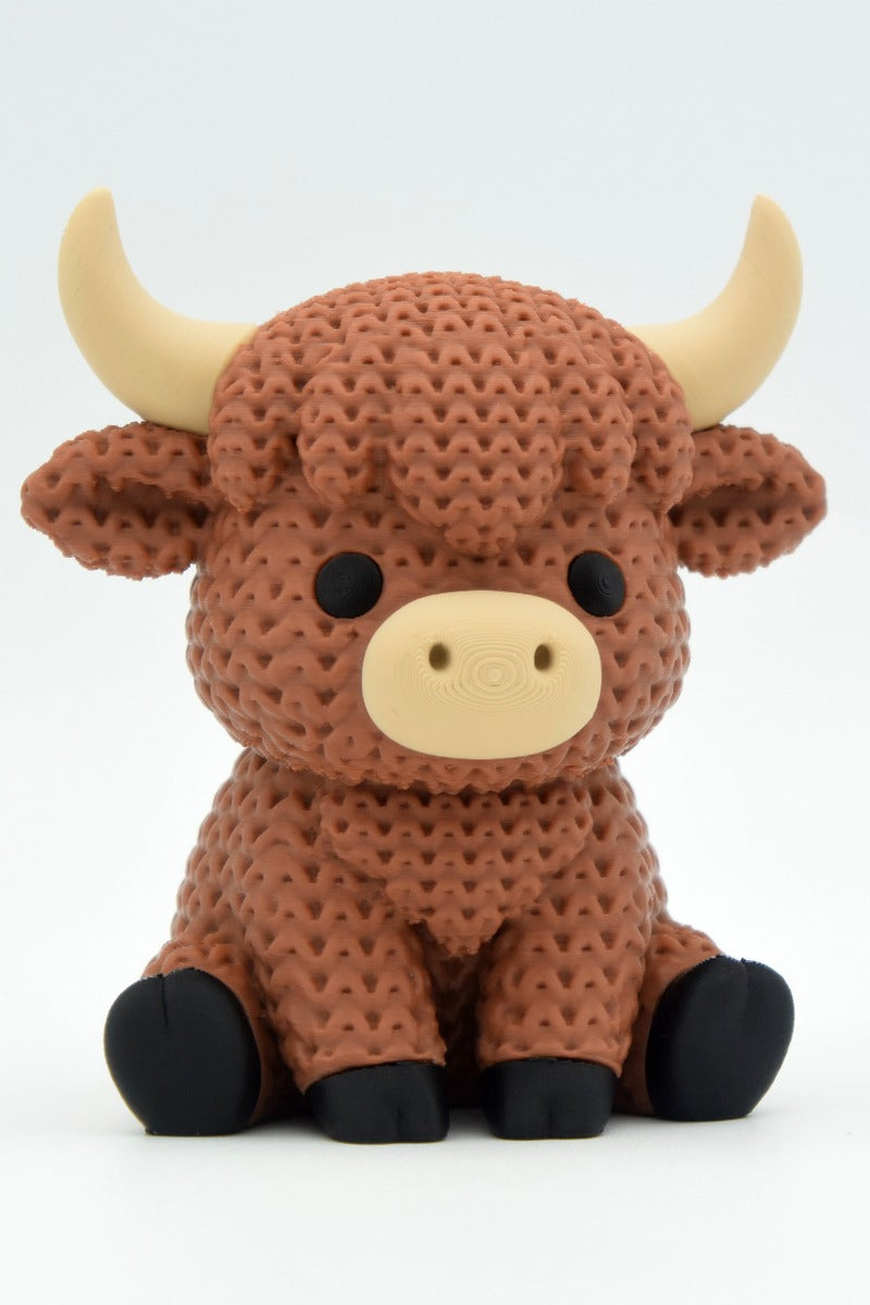Close-up of a knitted highland cow figurine with a textured crochet-look coat and small sculpted horns