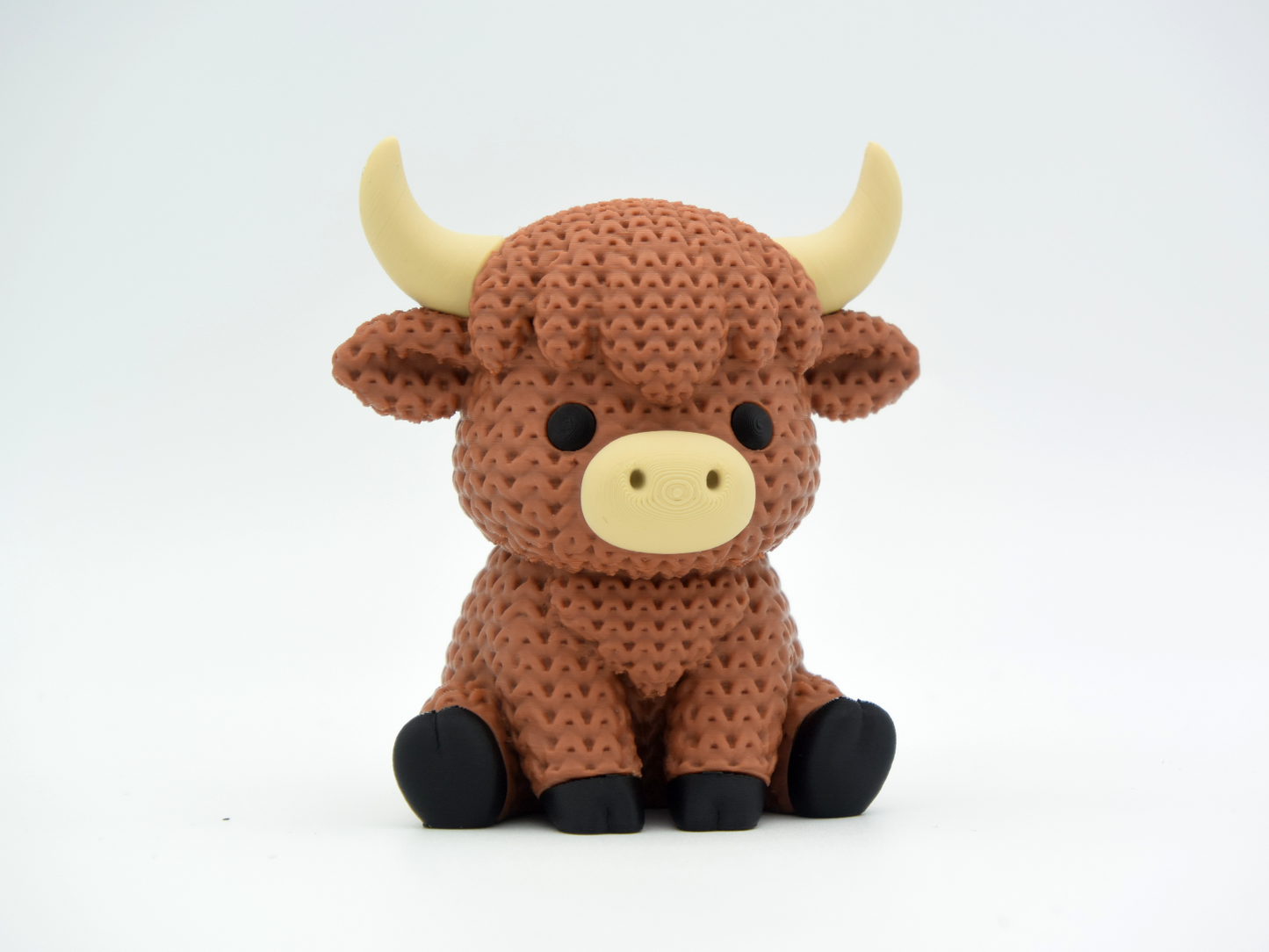 Close-up of a knitted highland cow figurine with a textured crochet-look coat and small sculpted horns