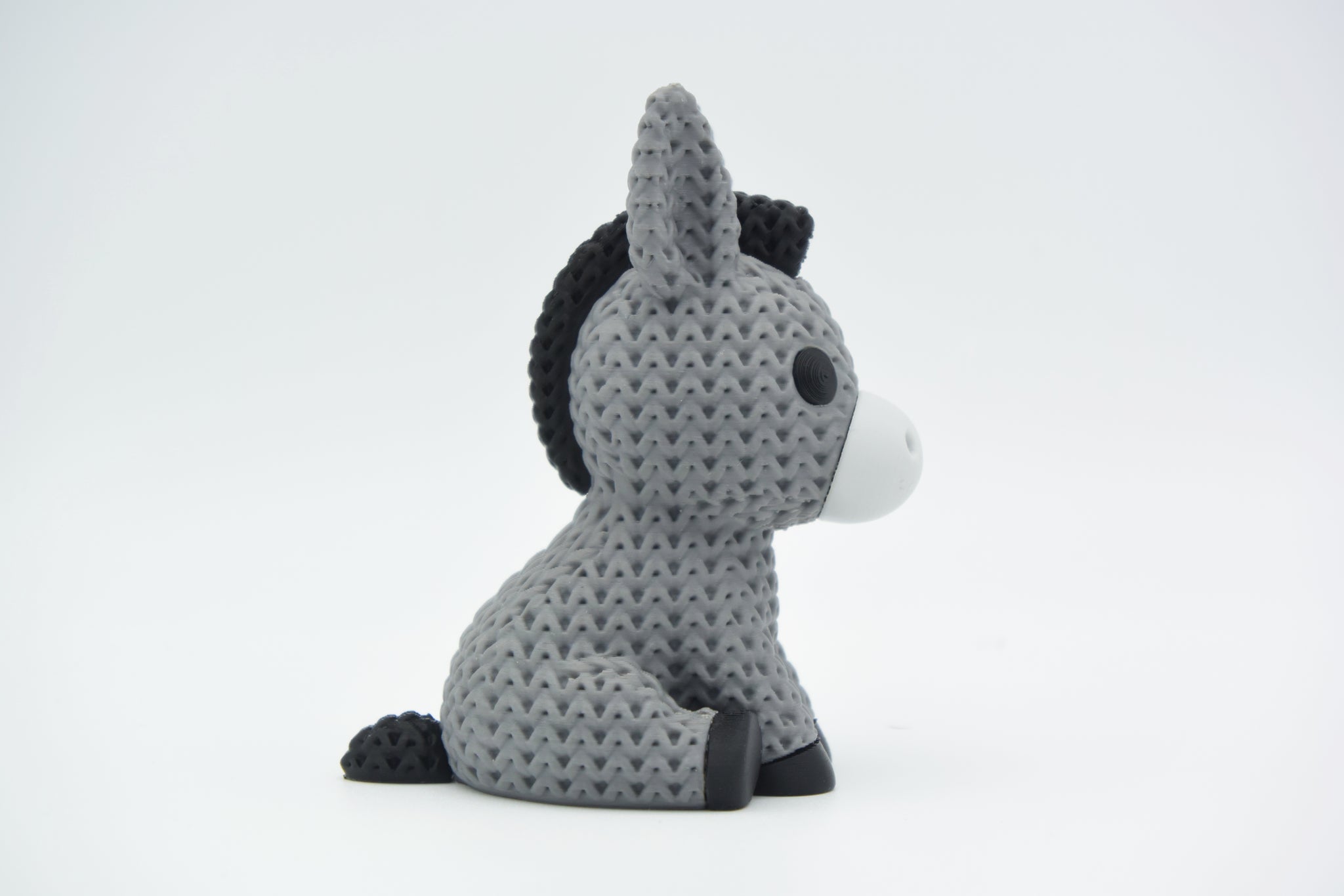 Knitted donkey figurine styled on a wooden shelf next to small plants and Scandinavian home decor