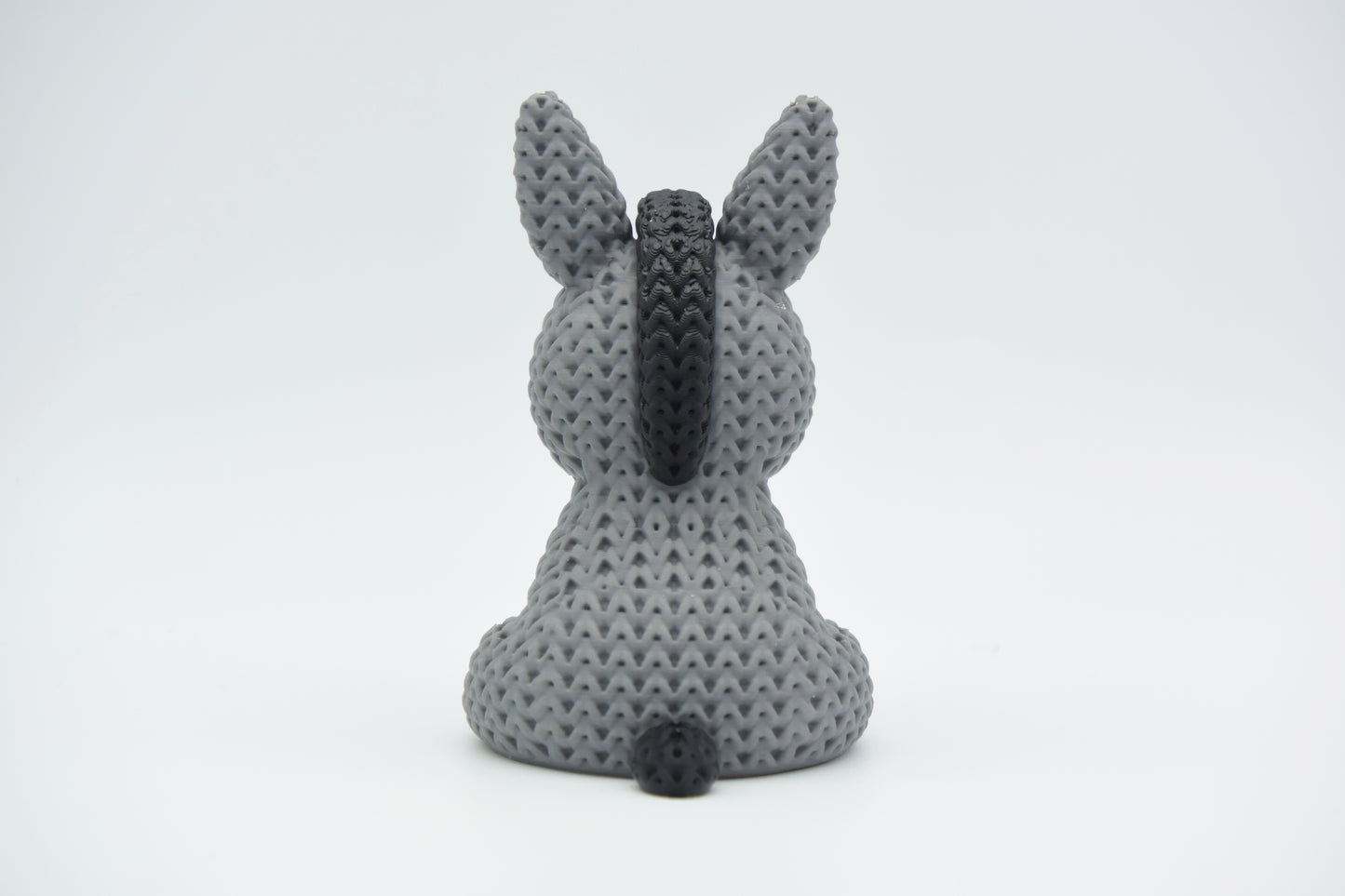 Texture detail of the knitted donkey showing the raised crochet-style surface pattern in warm light