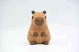 Close-up of a knitted capybara figure with soft crochet texture in warm brown tones, on a white surface