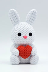 Close-up of a knitted bunny with heart decoration in soft white, showing textured surface detail, 49 DKK