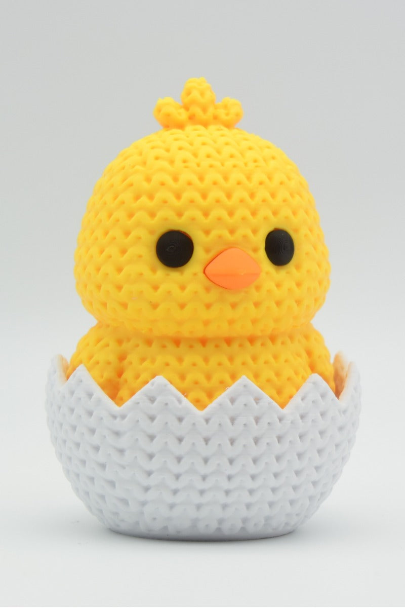 Close-up of a hatching chick Easter decoration with a soft knitted texture surface, shell and chick in pale yellow