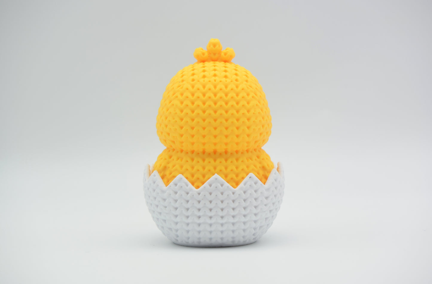 Texture detail of the knitted surface on a hatching chick Easter figure, showing the woven stitch pattern