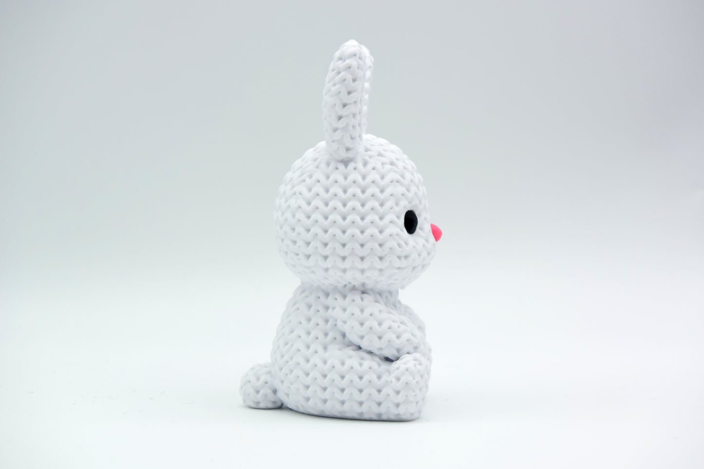 Close-up of a small knitted bunny decoration with soft crochet texture, white background, 49 DKK