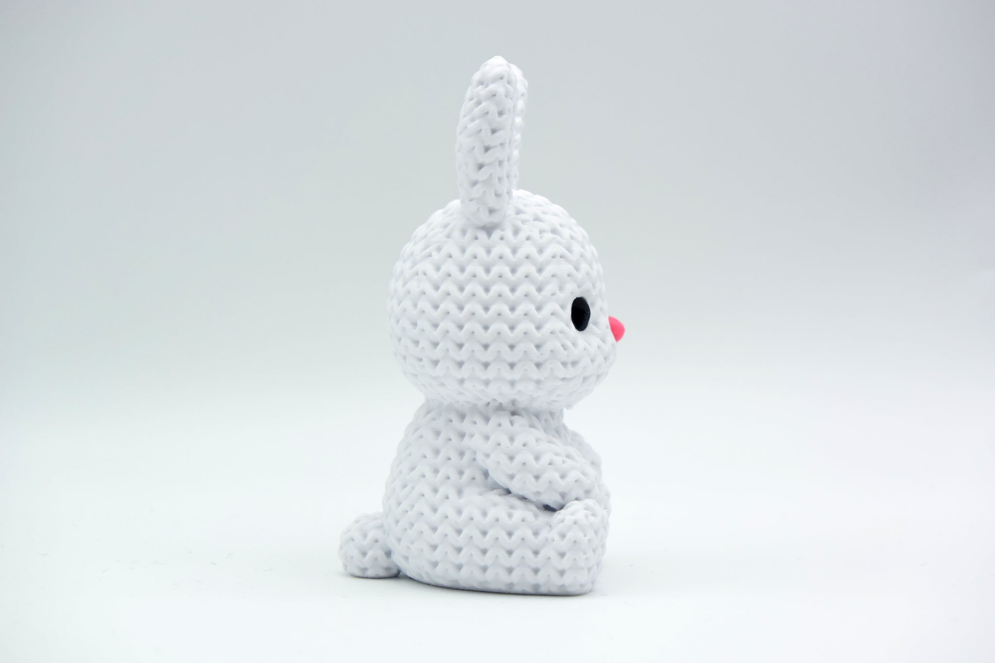 Close-up of a small knitted bunny decoration with soft crochet texture, white background, 49 DKK