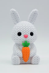 Close-up of a knitted bunny with carrot decoration showing soft looped texture and cream tones
