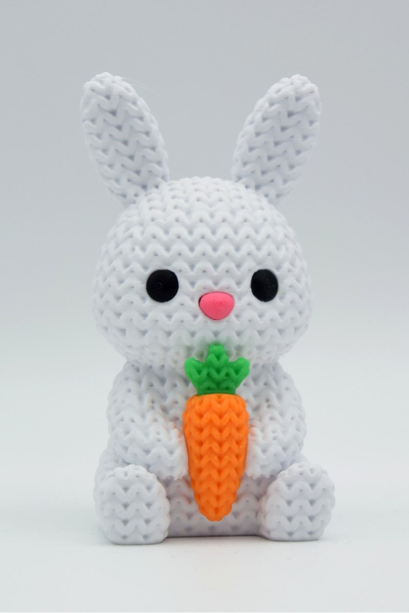 Close-up of a knitted bunny with carrot decoration showing soft looped texture and cream tones