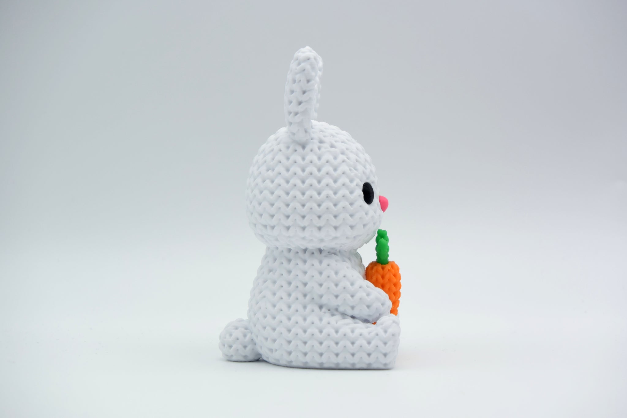 Close-up of a knitted bunny with carrot decoration showing soft looped texture and cream tones