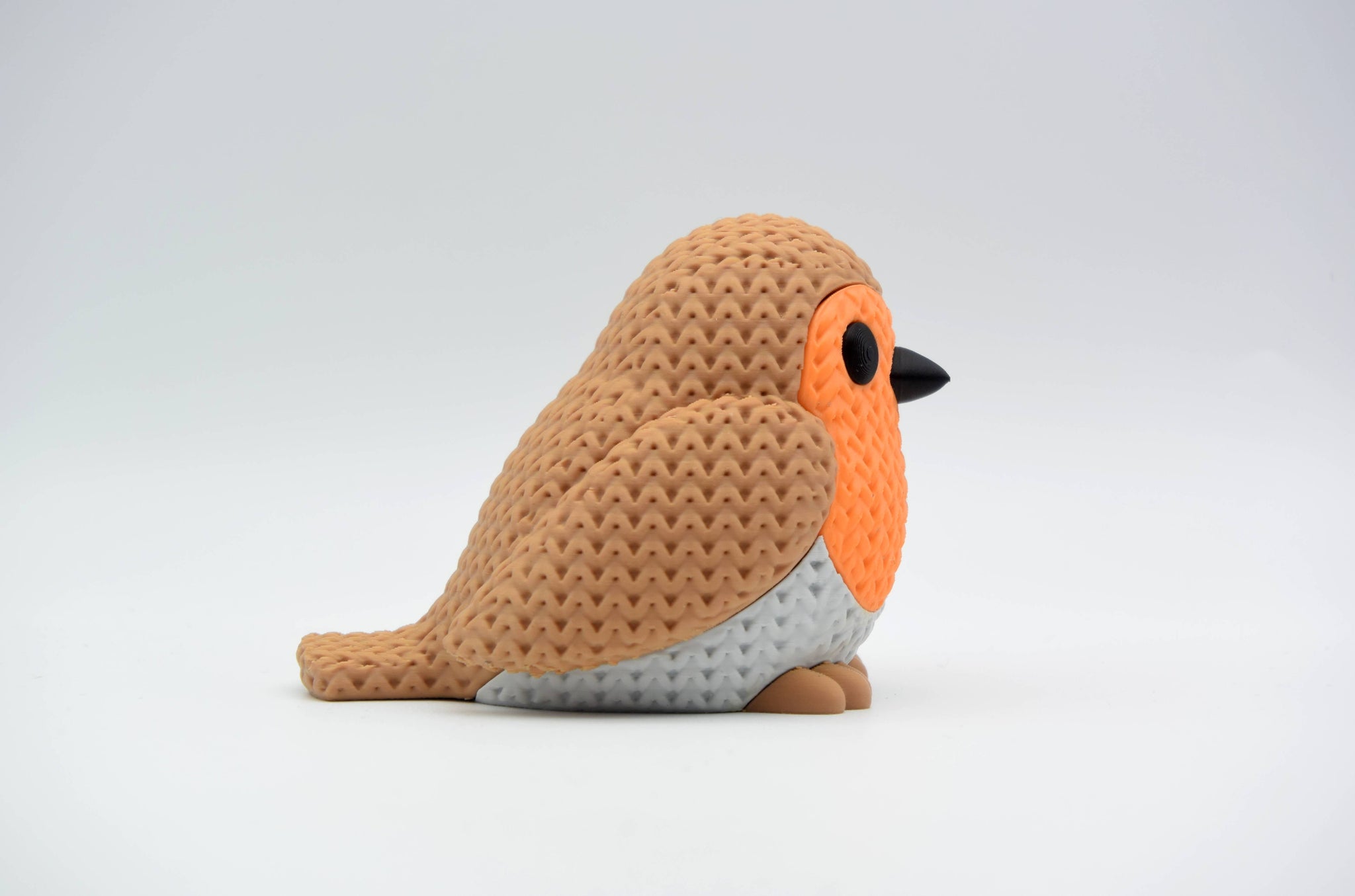 Small knitted robin bird decoration placed on a wooden shelf in a calm Scandinavian living room interior
