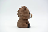 Knitted wild boar decorative figure styled on a wooden shelf next to natural home decor objects
