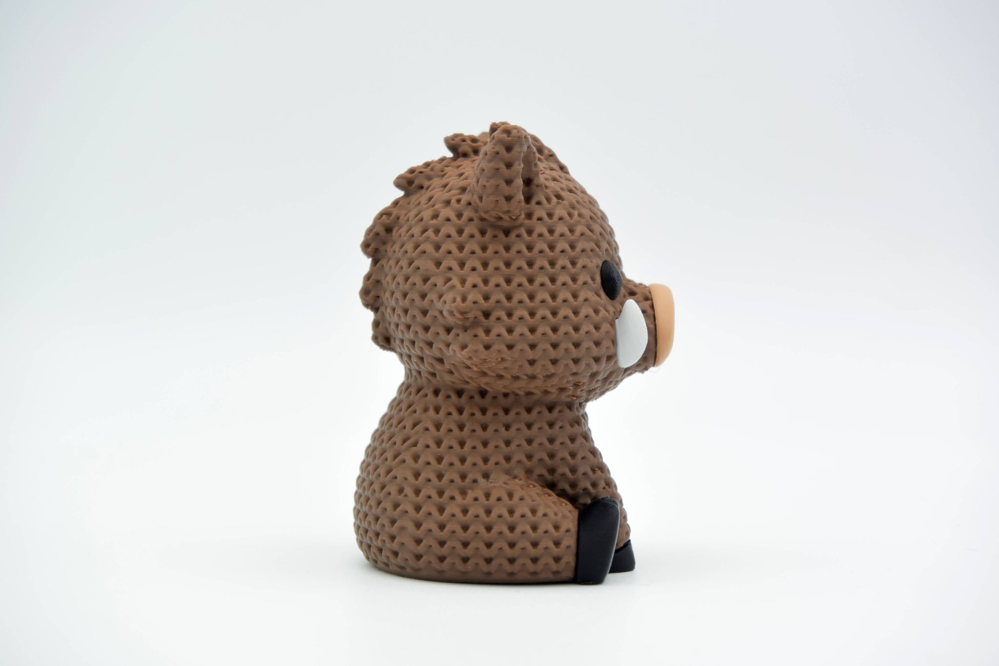 Knitted wild boar decorative figure styled on a wooden shelf next to natural home decor objects