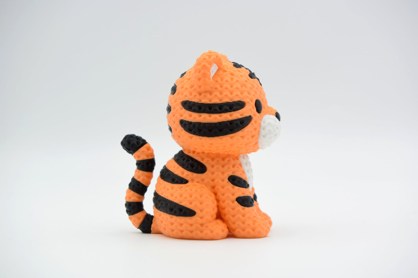Small knitted tiger figurine placed on a wooden shelf beside plants in a Scandinavian living room