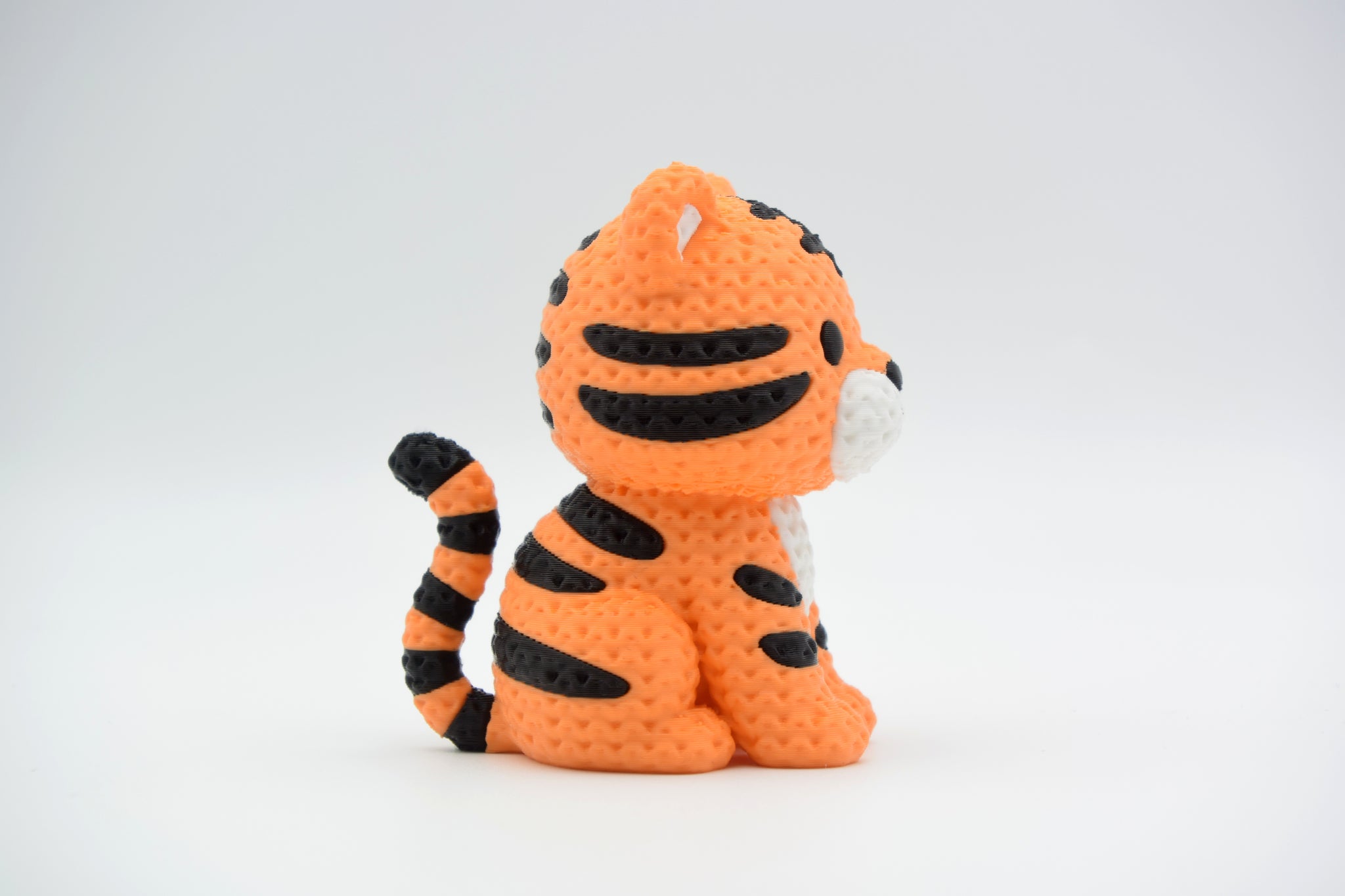 Small knitted tiger figurine placed on a wooden shelf beside plants in a Scandinavian living room