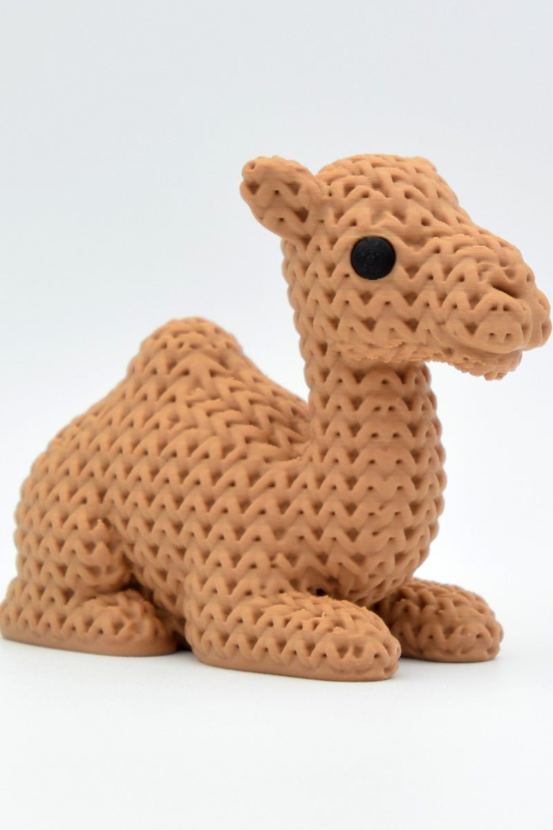 Close-up of a knitted camel figurine with a soft woven texture, shown against a white background