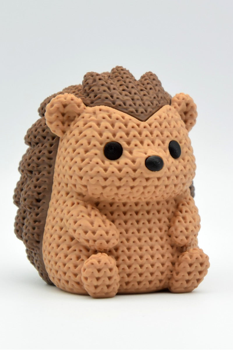 Close-up of a knitted hedgehog figurine with detailed crochet-texture surface, shown against a white background