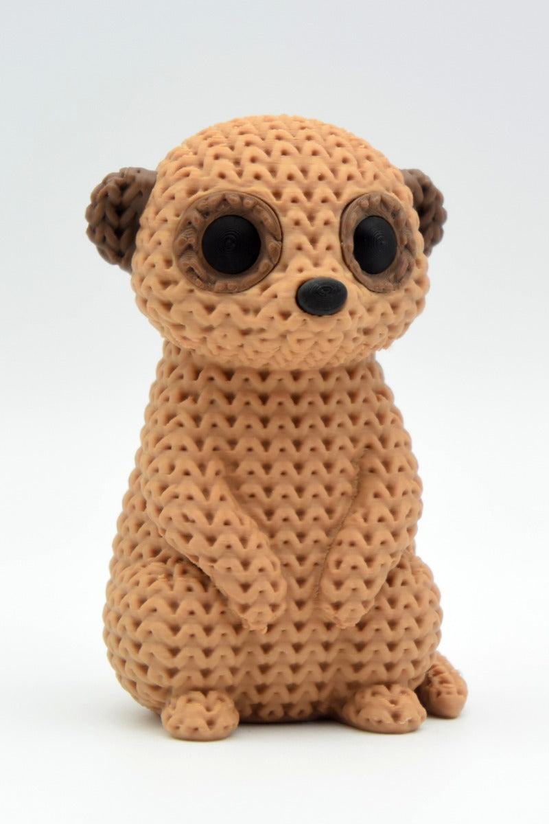 Close-up of a knitted meerkat figurine with a crochet-texture surface, standing upright on a white background