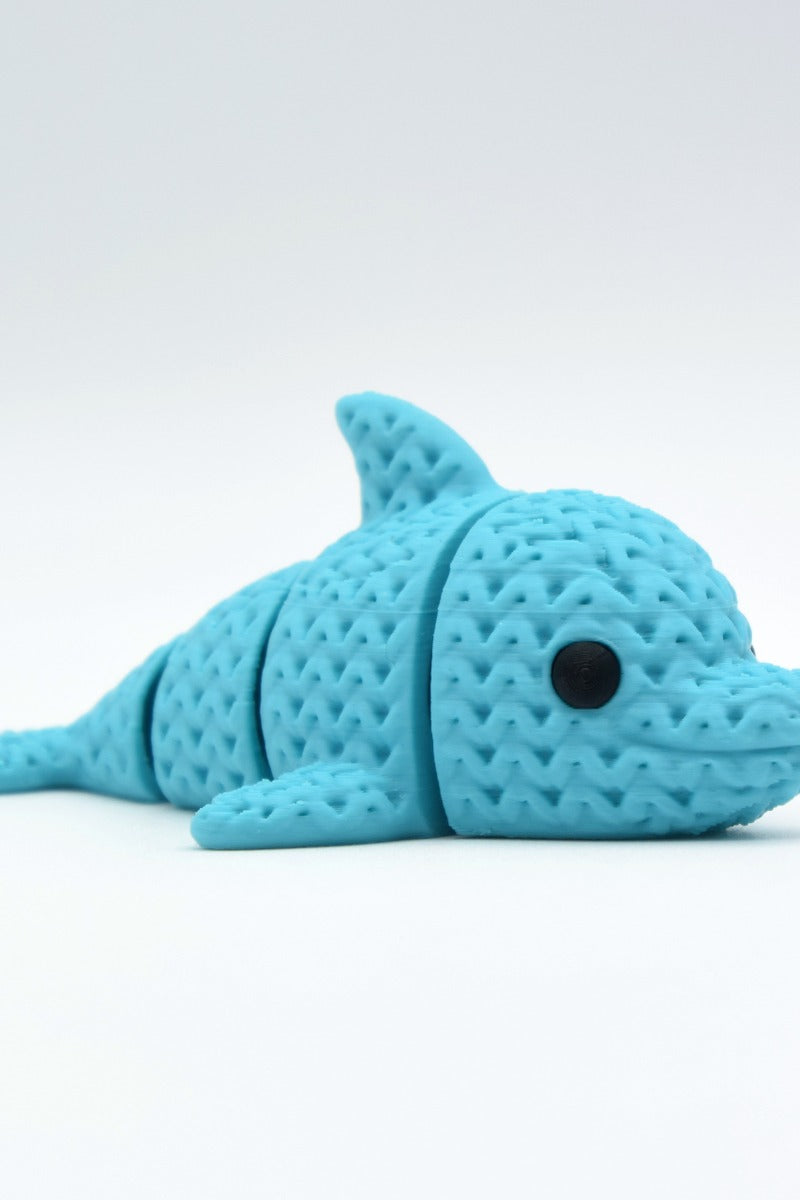 Close-up of a knitted articulated dolphin figurine with a soft crochet-textured surface, light grey colour