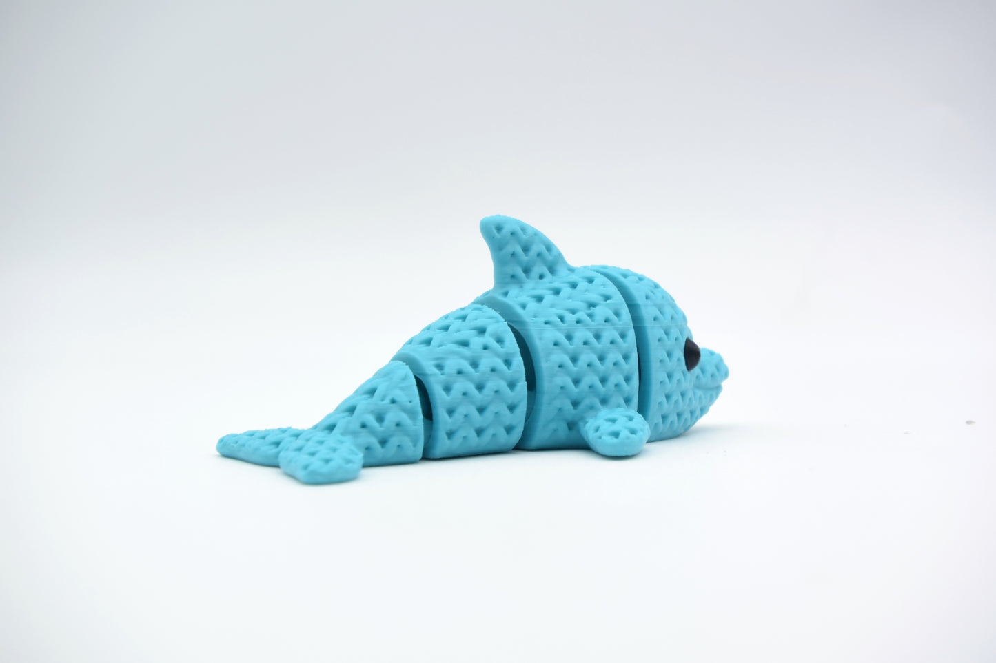 Texture detail of a knitted dolphin showing the woven surface pattern and segmented flexible body joints