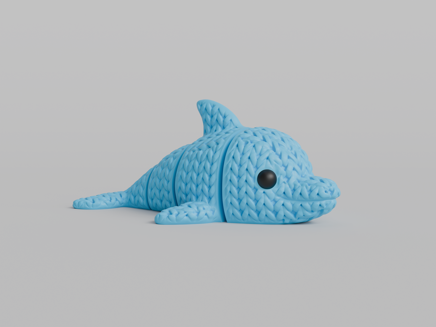 Close-up of a knitted articulated dolphin figurine with a soft crochet-textured surface, light grey colour