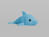 Close-up of a knitted articulated dolphin figurine with a soft crochet-textured surface, light grey colour