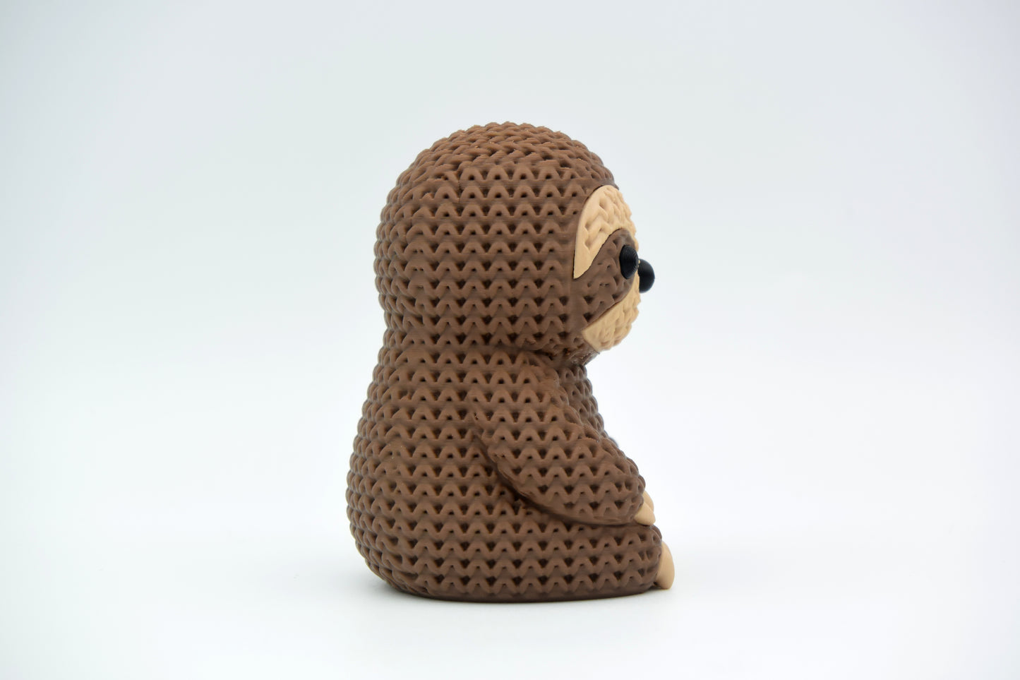 Close-up of a knitted sloth figurine with a soft crochet-look texture in warm tones, approx. 10 cm