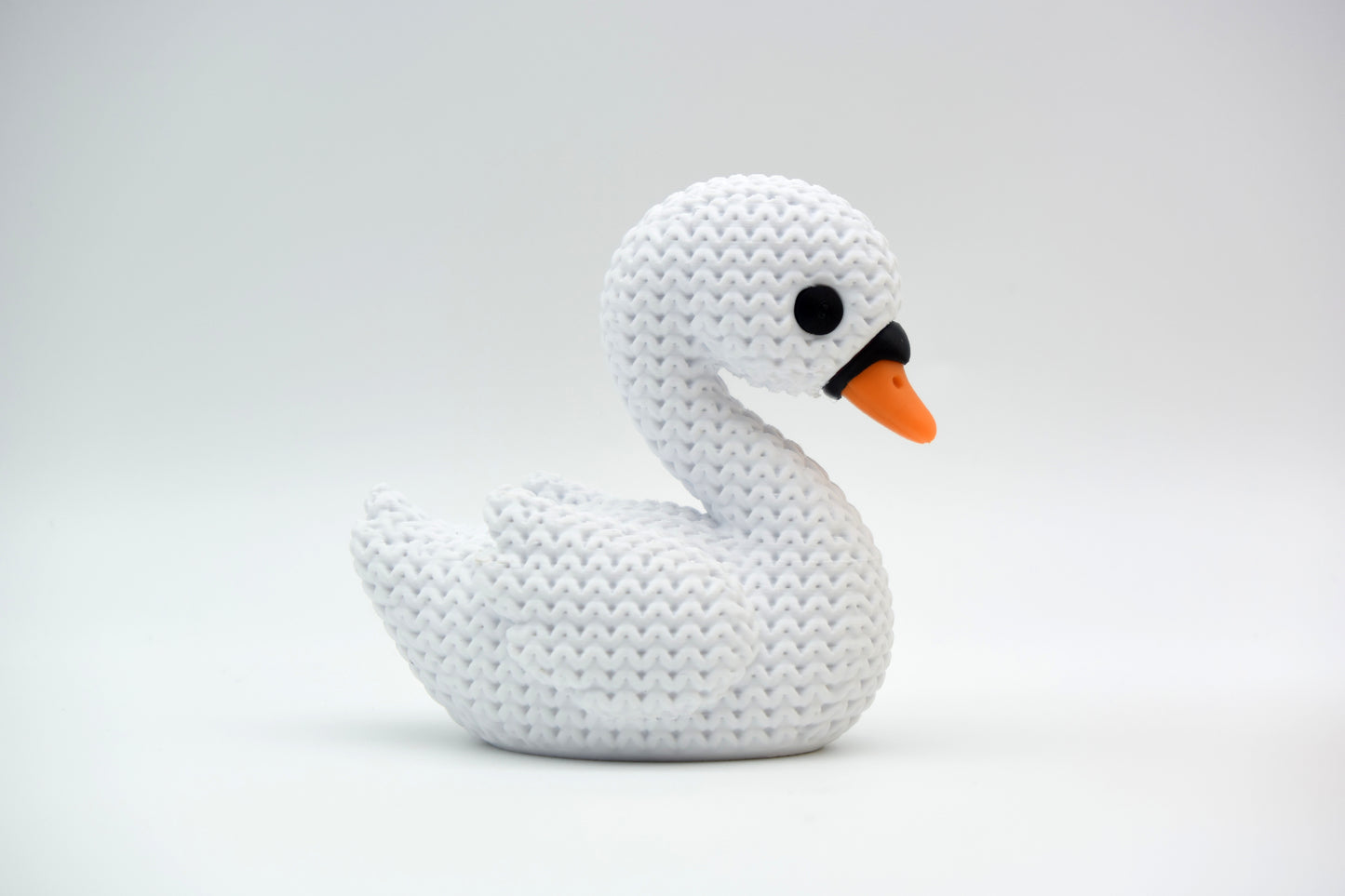 White knitted swan decoration styled on a wooden shelf beside dried flowers and neutral home decor