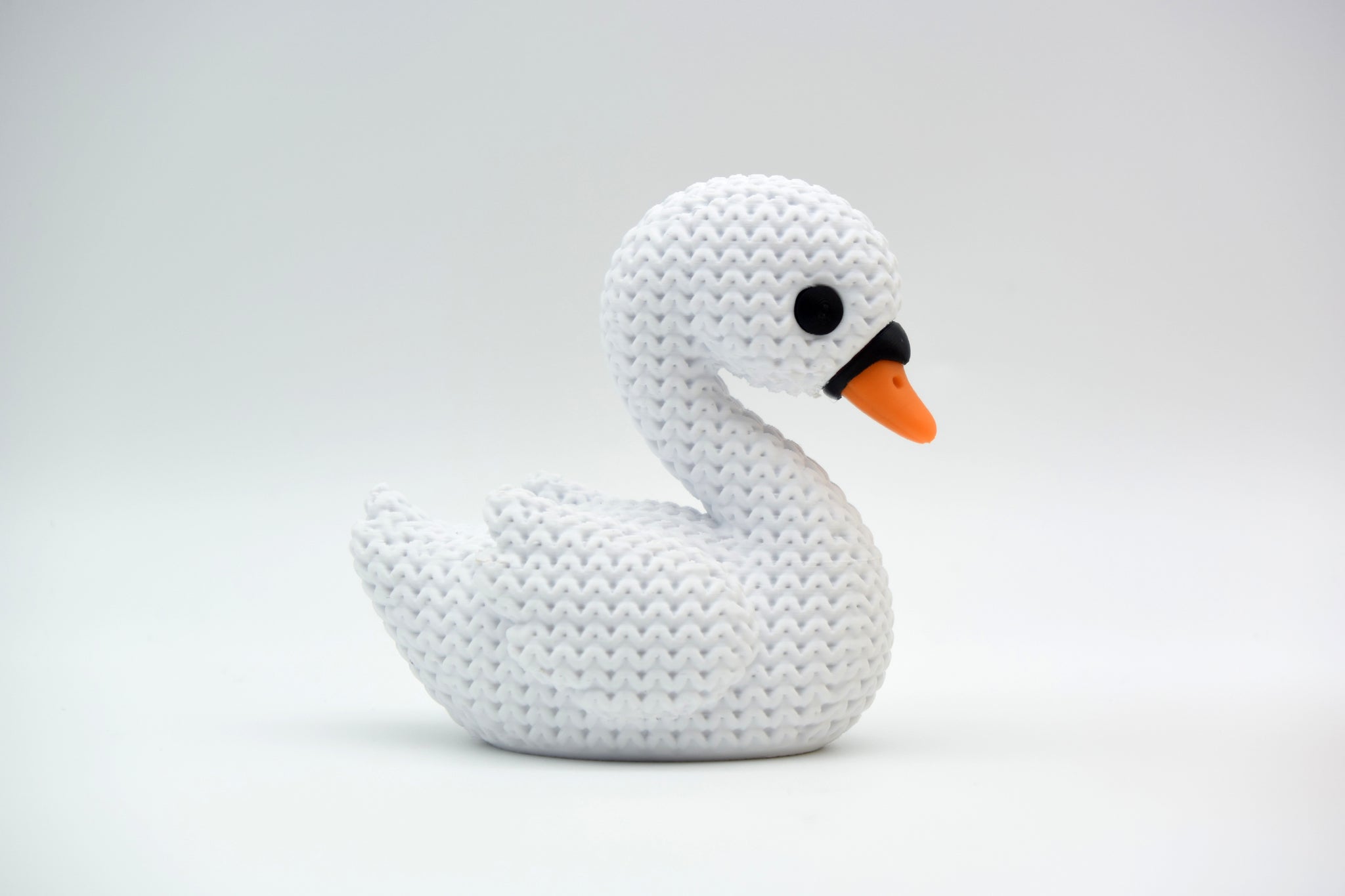 White knitted swan decoration styled on a wooden shelf beside dried flowers and neutral home decor