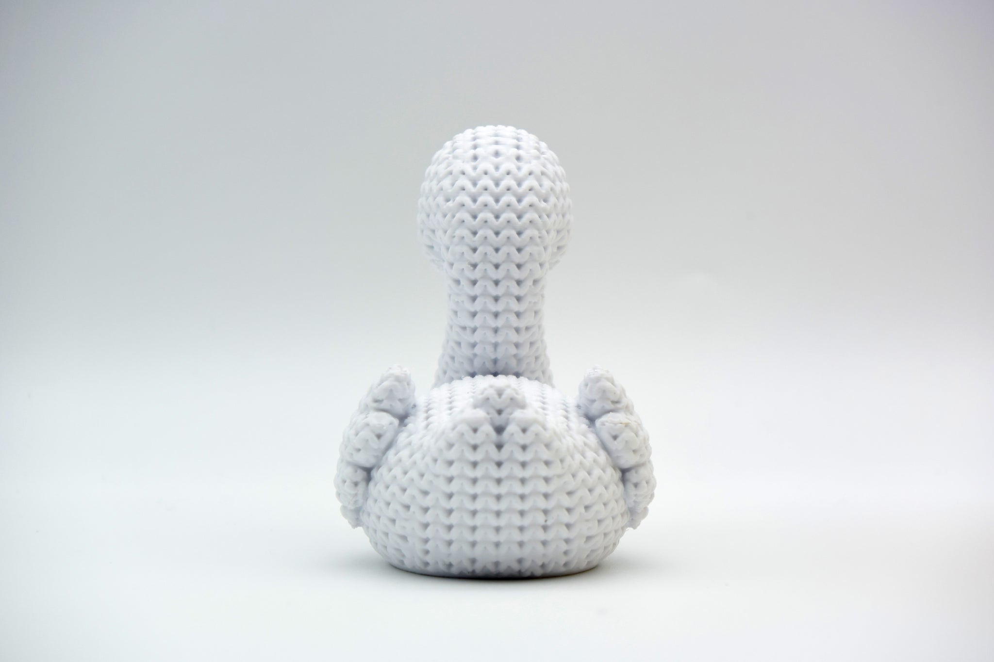 Detail shot of the woven surface texture on a knitted swan figurine, showing the stitch-like pattern