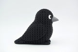 Decorative knitted crow placed on a wooden shelf in a calm Scandinavian living room setting