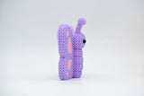 Knitted butterfly decoration placed on a wooden shelf beside a small plant in a Scandinavian home