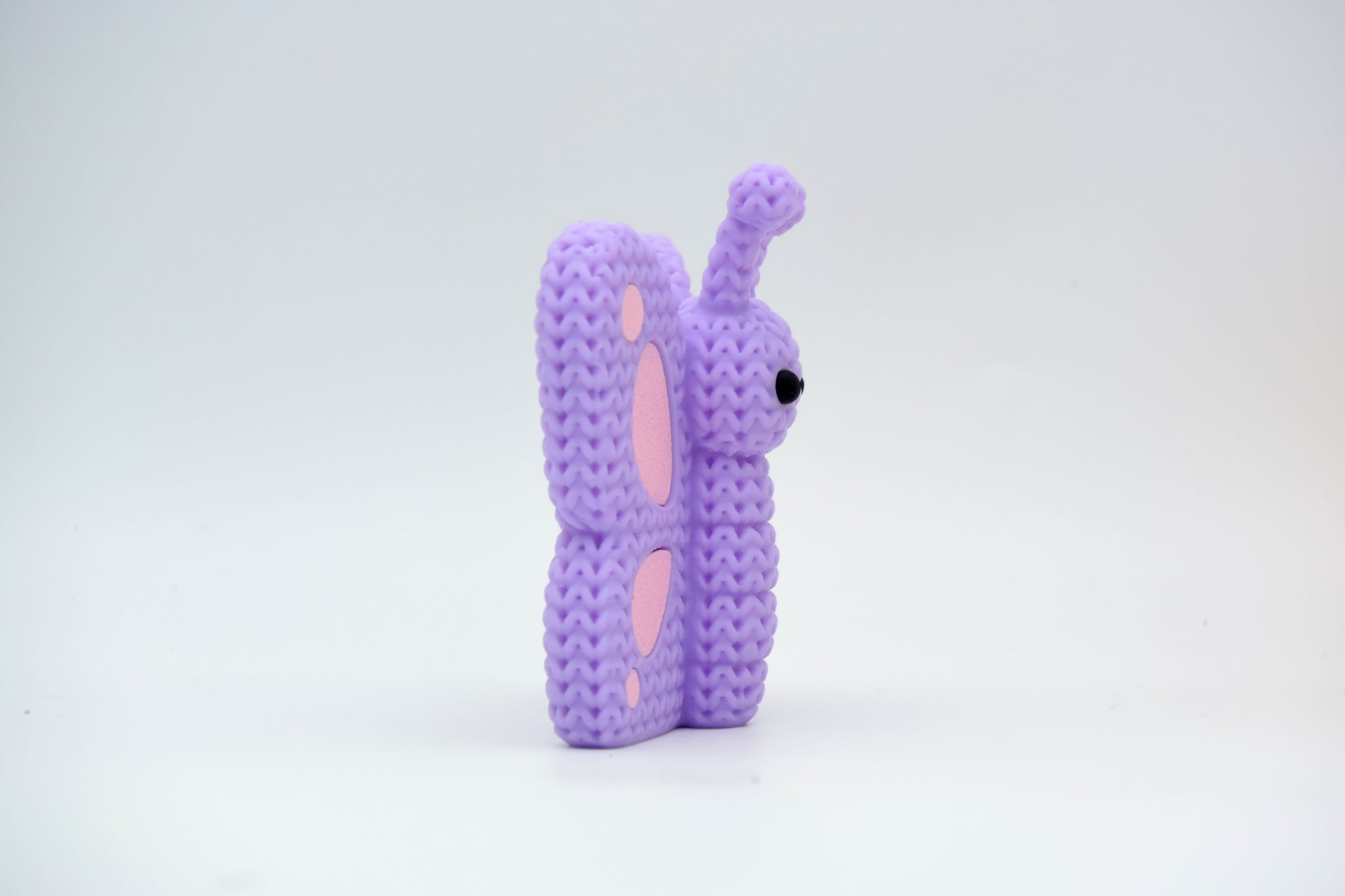 Knitted butterfly decoration placed on a wooden shelf beside a small plant in a Scandinavian home