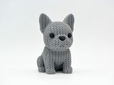 Close-up of a knitted French Bulldog decorative figure with a textured crochet-like coat, shown on a light surface