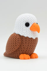Close-up of a knitted eagle figurine with crochet-look texture and detailed feather ridges, shot on a white surface