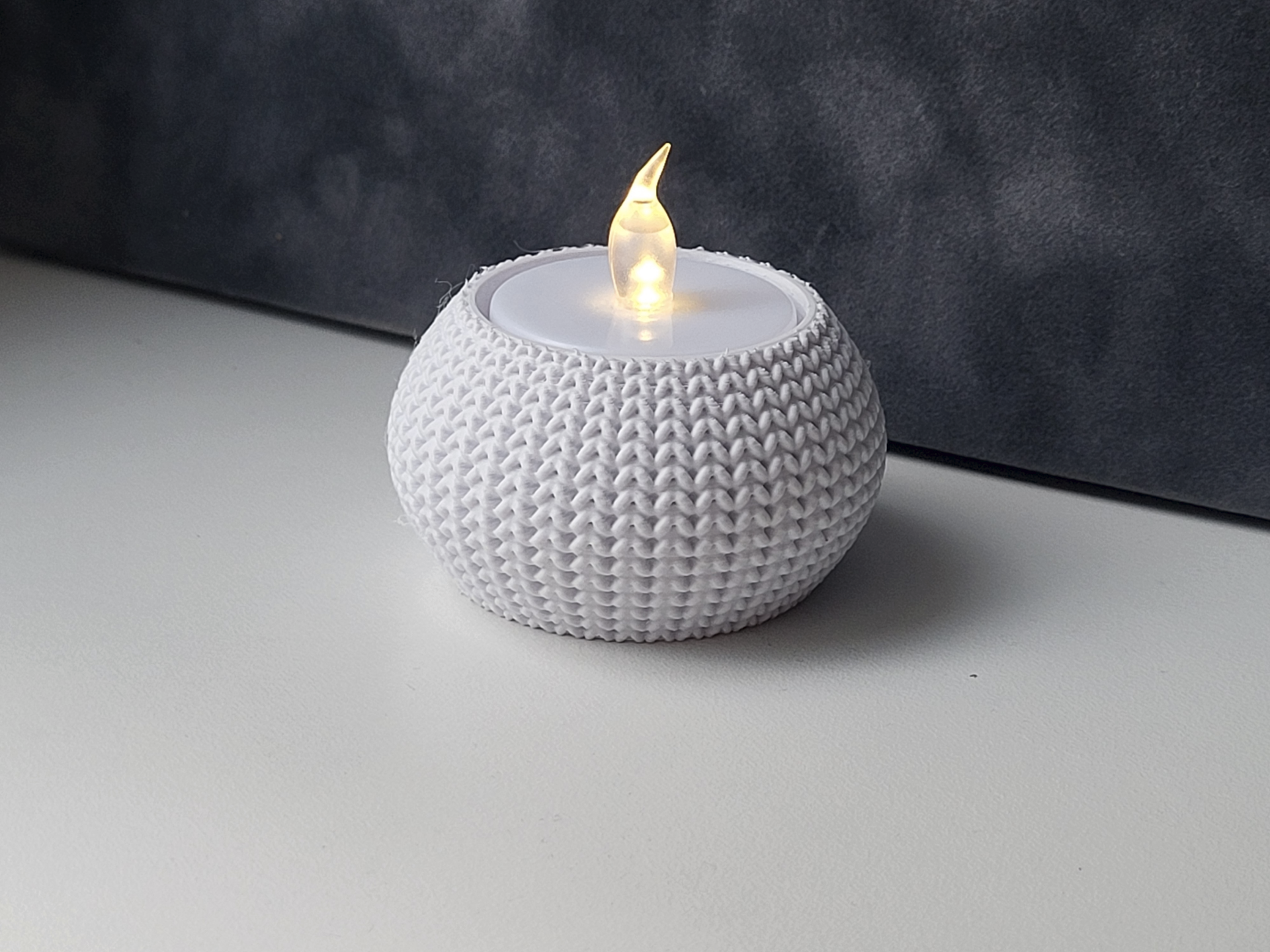 Detail of the open knit pattern on a tea light holder, showing texture and warm candlelight through the weave