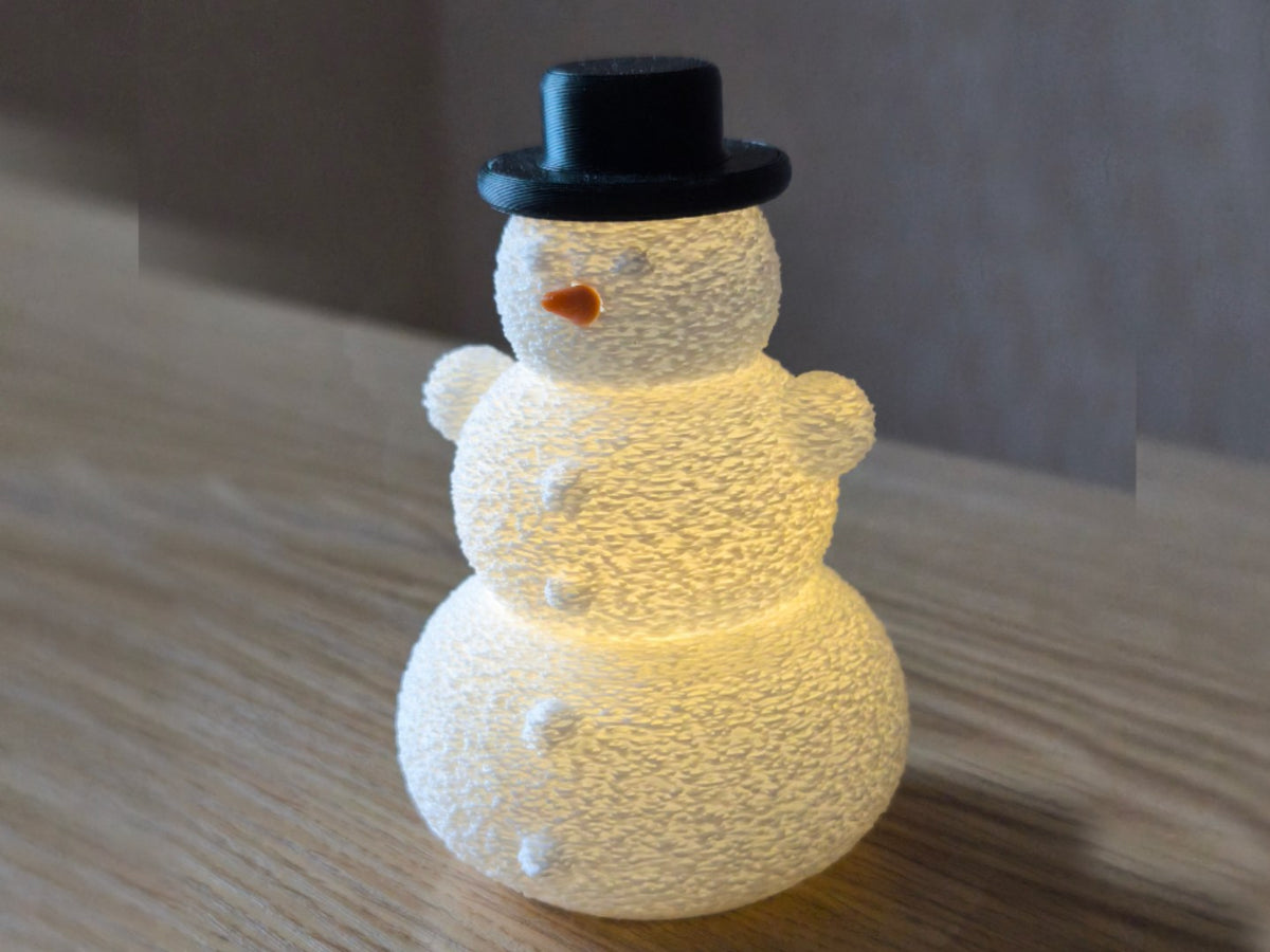 Schneemann mit Hut und Nase über einem LED-Teelicht