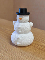 Schneemann mit Hut und Nase über einem LED-Teelicht